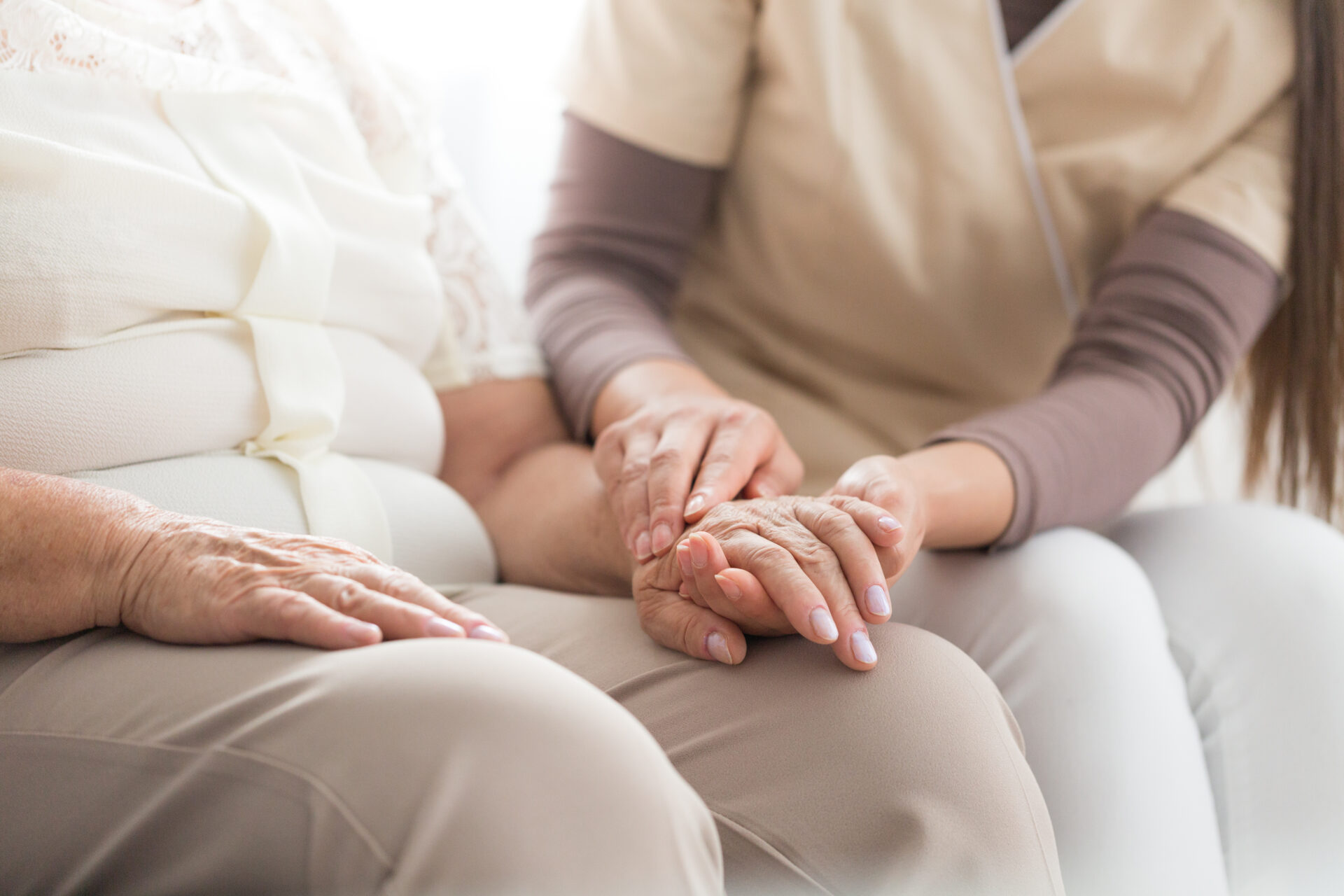 Close-up of nurse taking care about elderly person with parkinson while sitting together at home
