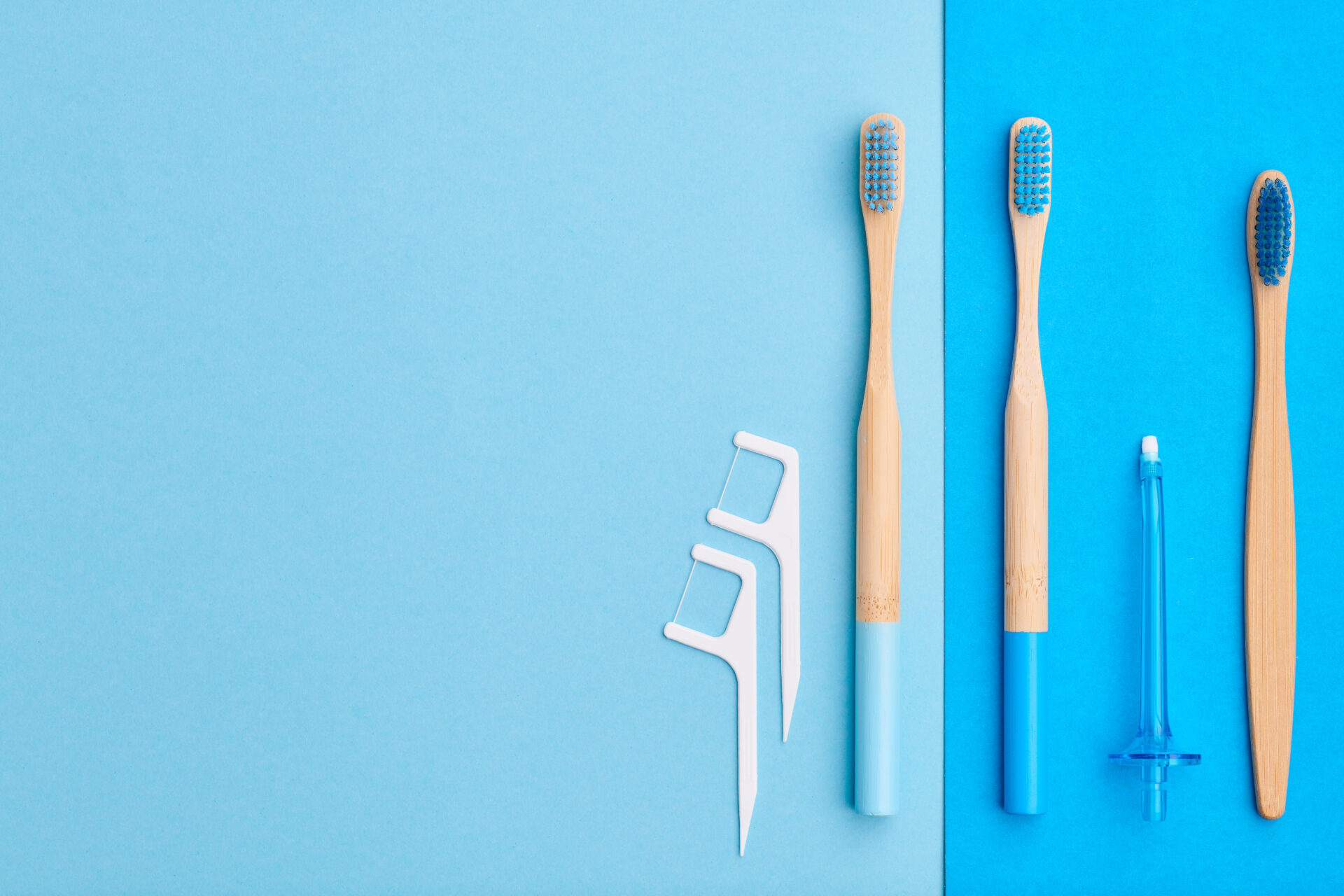 Toothbrushes and oral care tools over blue background top view copy space flat lay. Tooth care, dental hygiene and health concept.