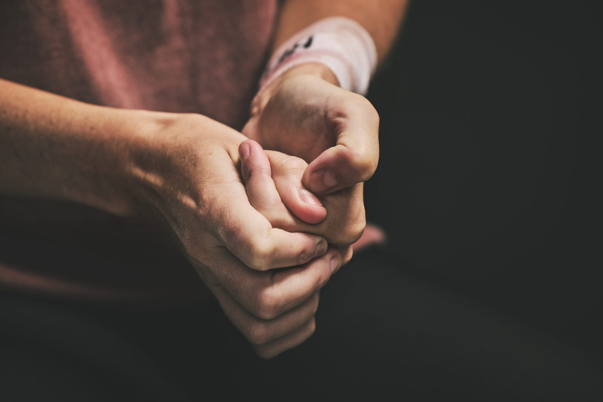 Person with a bandaged wrist and picking at their finger nails to represent self-harm.